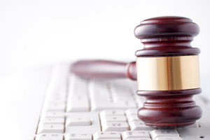 Conceptual image of a gavel used by a judge or auctioneer with a brass band around the head lying on a computer keyboard